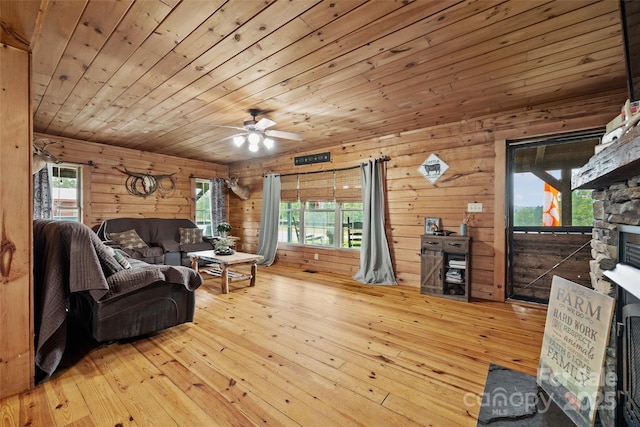 living room with wood ceiling, ceiling fan, a fireplace, light hardwood / wood-style floors, and wood walls