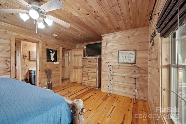 bedroom with wood walls, wooden ceiling, ensuite bathroom, and light wood-type flooring