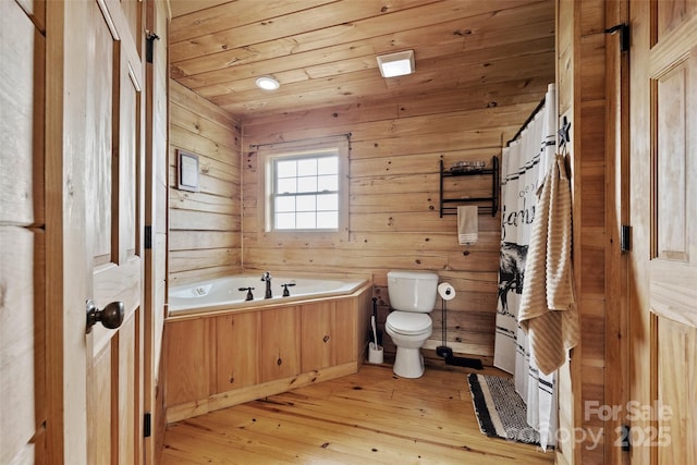 bathroom featuring hardwood / wood-style floors, wooden walls, toilet, a tub to relax in, and wood ceiling