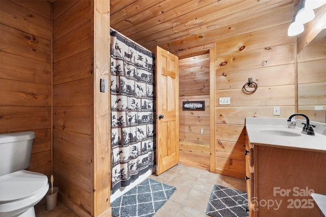 bathroom with vanity, wood walls, wooden ceiling, tile patterned floors, and toilet