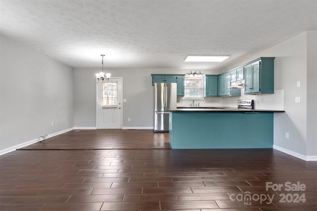 kitchen with appliances with stainless steel finishes, a textured ceiling, dark hardwood / wood-style floors, and decorative light fixtures