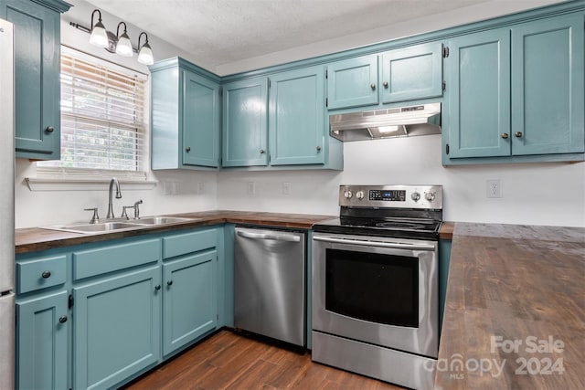 kitchen featuring a textured ceiling, dark hardwood / wood-style floors, sink, stainless steel appliances, and blue cabinetry