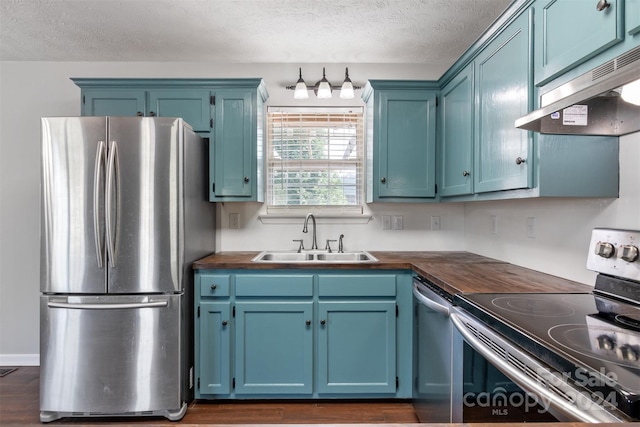 kitchen with sink, a textured ceiling, dark wood-type flooring, blue cabinetry, and appliances with stainless steel finishes