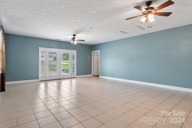 empty room featuring ceiling fan, a textured ceiling, french doors, and light tile patterned floors