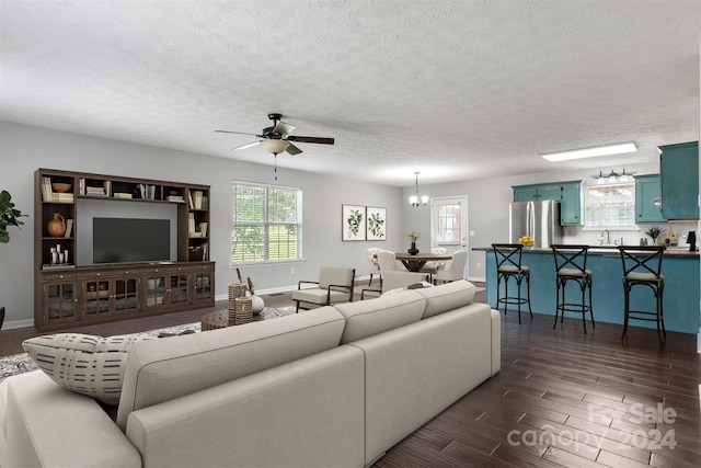 living room featuring ceiling fan with notable chandelier, a textured ceiling, sink, and dark hardwood / wood-style flooring