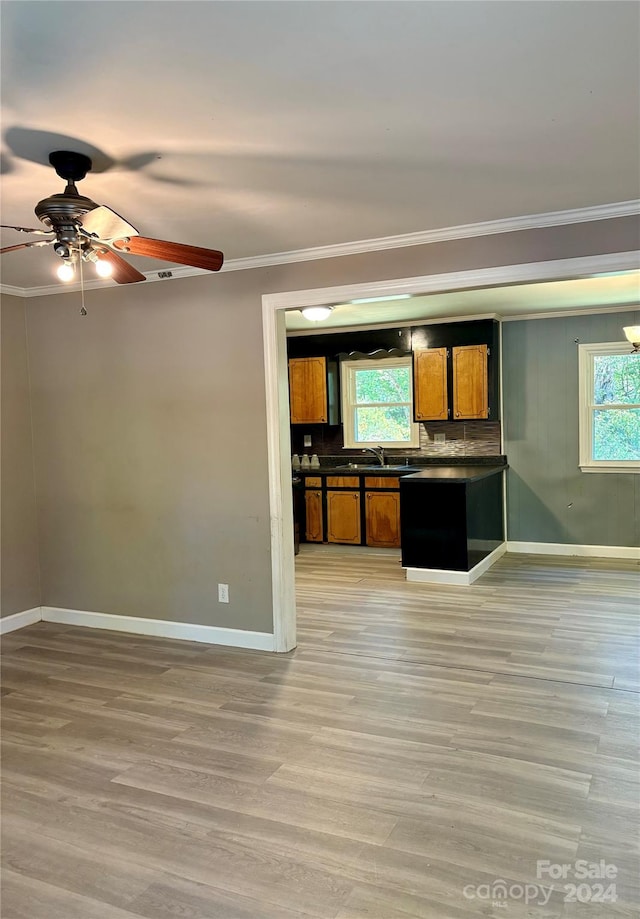 kitchen featuring sink, light wood-type flooring, backsplash, ceiling fan, and ornamental molding