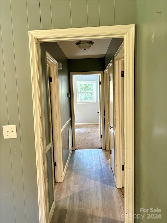 hallway featuring light hardwood / wood-style floors and wood walls