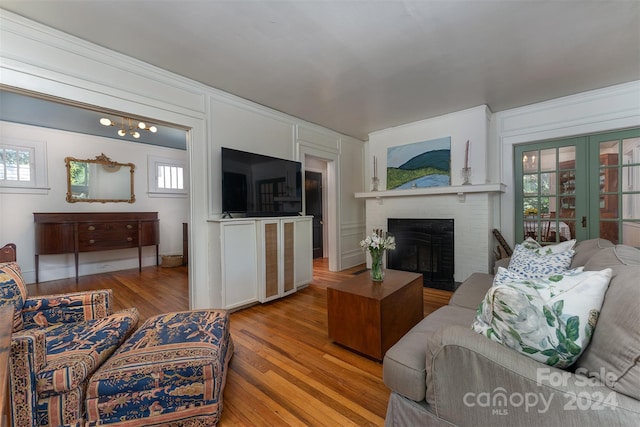 living room featuring hardwood / wood-style floors, plenty of natural light, french doors, and a brick fireplace