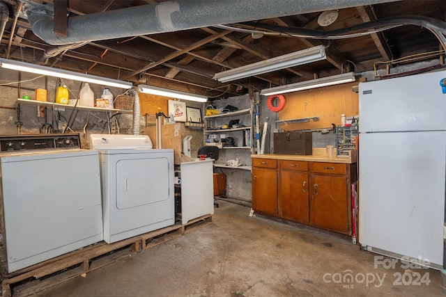 basement with washing machine and dryer and white fridge