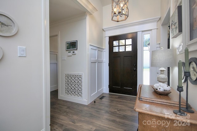 entryway featuring ornamental molding, a chandelier, and dark wood-type flooring