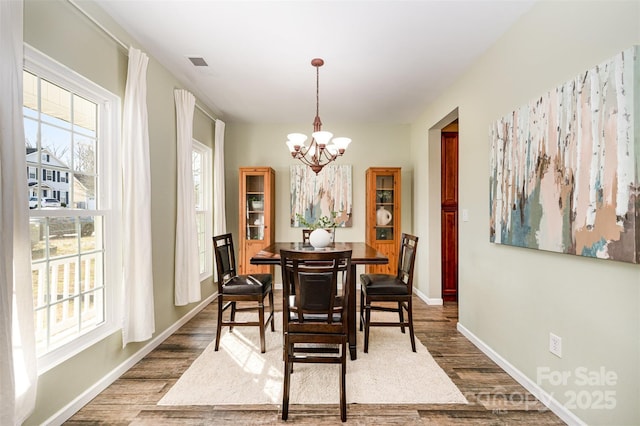 dining area featuring plenty of natural light, dark wood-type flooring, and an inviting chandelier