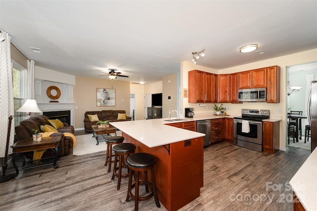 kitchen with kitchen peninsula, stainless steel appliances, a breakfast bar, sink, and dark hardwood / wood-style floors