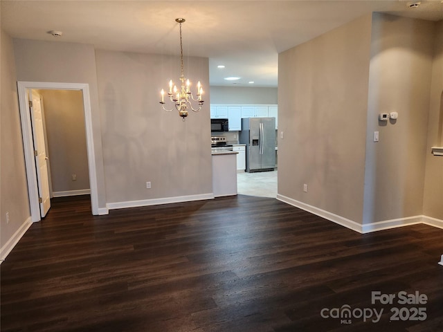 unfurnished dining area featuring recessed lighting, baseboards, an inviting chandelier, and wood finished floors