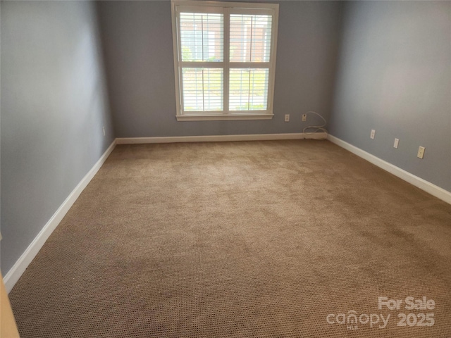 carpeted spare room featuring baseboards