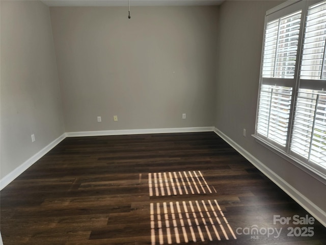 empty room featuring dark wood-type flooring and baseboards