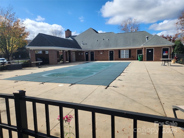 community pool with a patio and fence