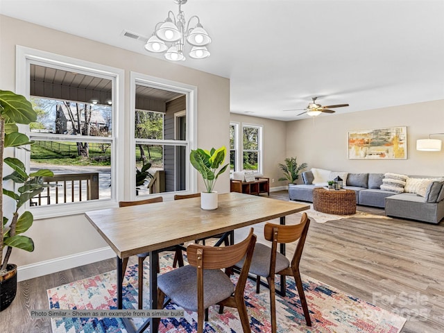 dining space featuring hardwood / wood-style flooring and ceiling fan with notable chandelier