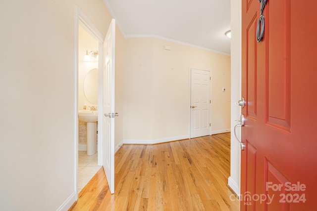 hallway with light hardwood / wood-style floors and ornamental molding