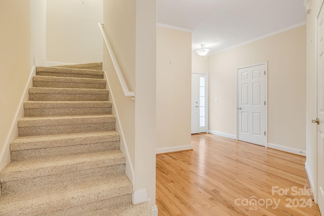 staircase featuring wood-type flooring and crown molding