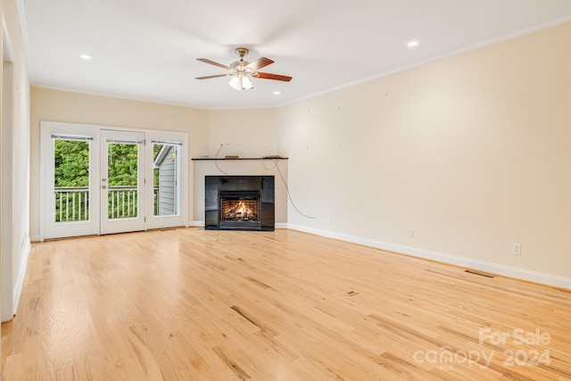 unfurnished living room featuring a tile fireplace, crown molding, ceiling fan, and light hardwood / wood-style flooring