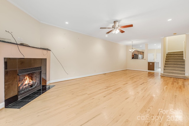 unfurnished living room with a tile fireplace, crown molding, ceiling fan, and wood-type flooring