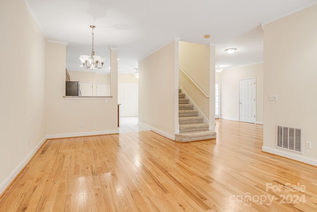 empty room with crown molding, light hardwood / wood-style floors, and an inviting chandelier