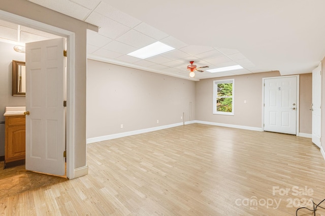 interior space with ceiling fan, a drop ceiling, and light hardwood / wood-style floors