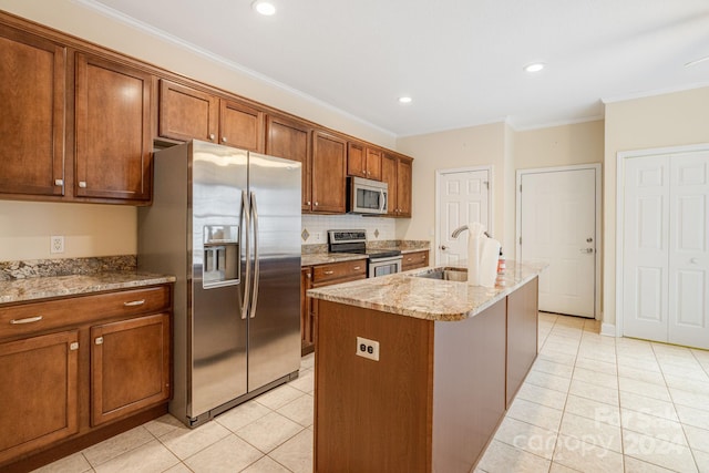 kitchen with an island with sink, stainless steel appliances, ornamental molding, and light tile patterned flooring