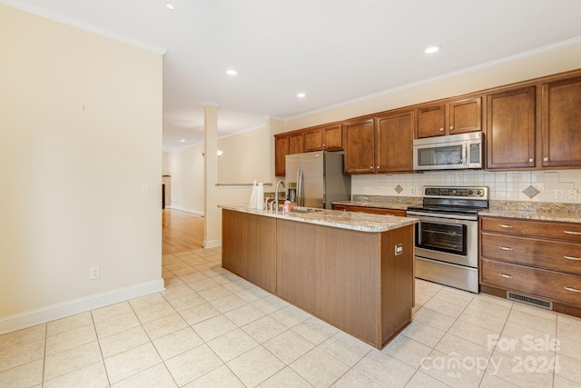 kitchen featuring an island with sink, appliances with stainless steel finishes, and ornamental molding