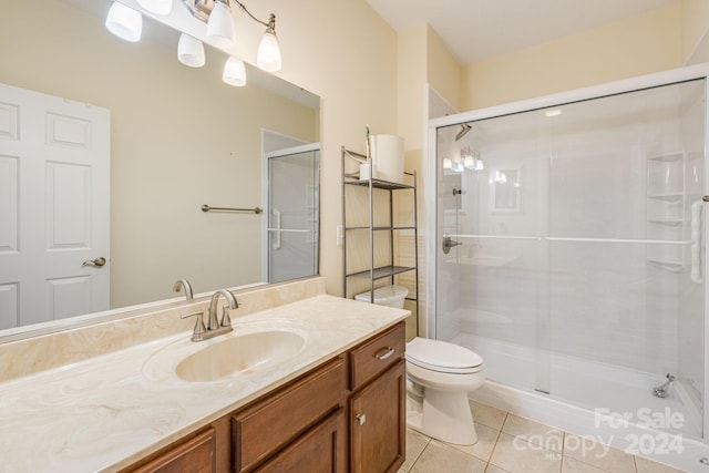 bathroom with tile patterned flooring, vanity, toilet, and a shower with shower door