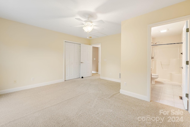 unfurnished bedroom with light carpet, a closet, ceiling fan, and ensuite bathroom