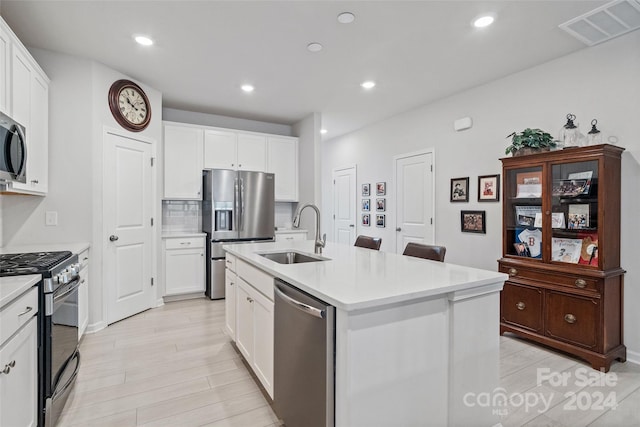 kitchen featuring white cabinetry, sink, appliances with stainless steel finishes, and an island with sink