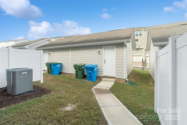 back of house featuring a lawn and central air condition unit