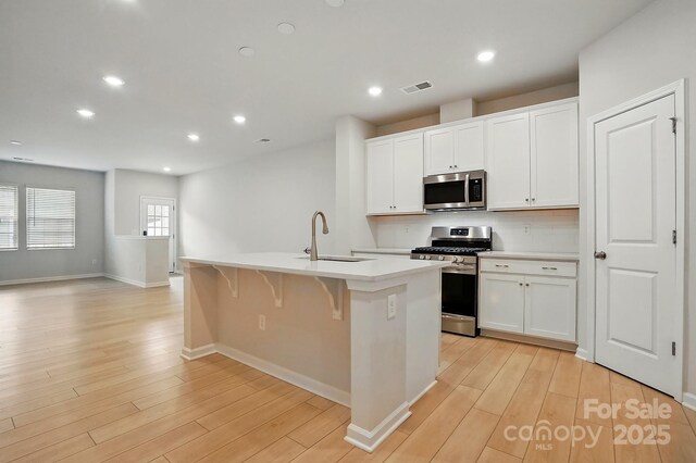 939 Cobbled Way, Fort Mill, SC 29715 - kitchen with appliances with stainless steel finishes, a sink, a center island with sink, light wood-style floors, and recessed lighting