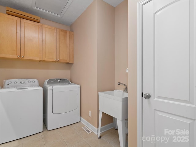 clothes washing area featuring cabinets, separate washer and dryer, and light tile patterned floors