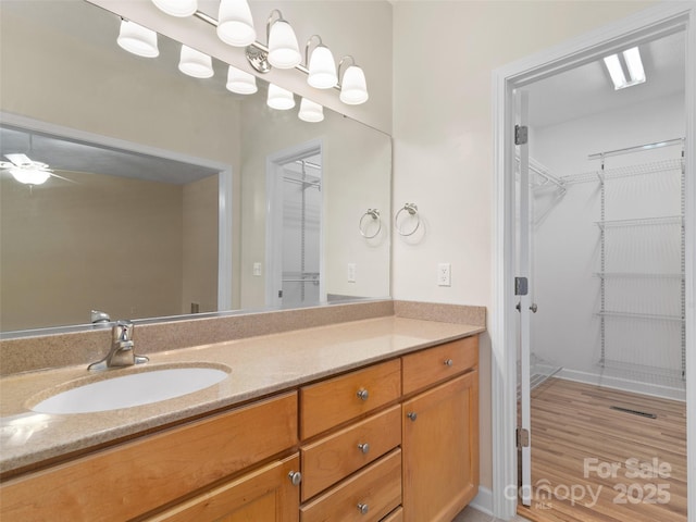 bathroom with ceiling fan, vanity, and wood-type flooring