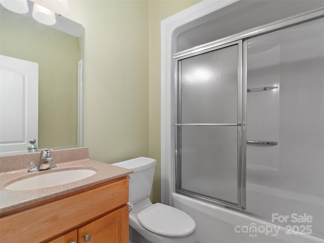 full bathroom with enclosed tub / shower combo, vanity, and toilet