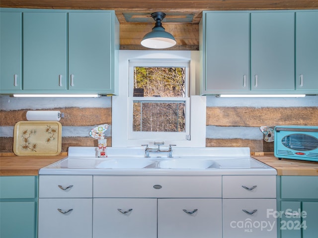 kitchen featuring blue cabinets, sink, and pendant lighting