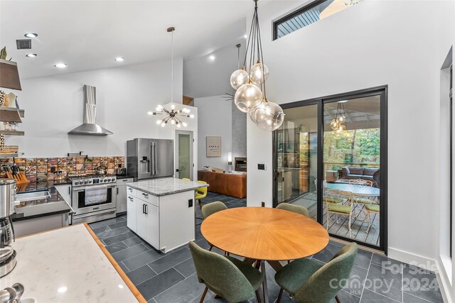 dining area with a notable chandelier, dark tile patterned floors, and high vaulted ceiling