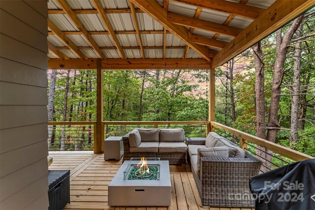 wooden terrace with an outdoor living space with a fire pit