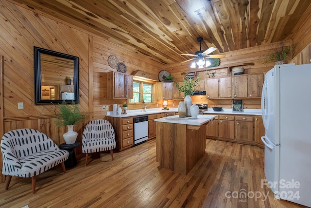 kitchen with white appliances, wood walls, a center island, ceiling fan, and hardwood / wood-style flooring