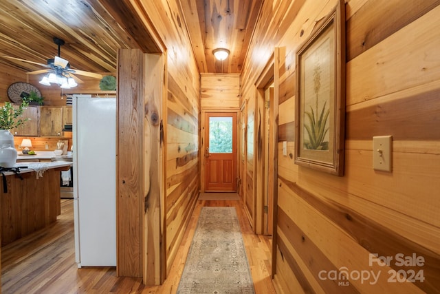 interior space with ceiling fan, wood ceiling, wood walls, and light hardwood / wood-style floors