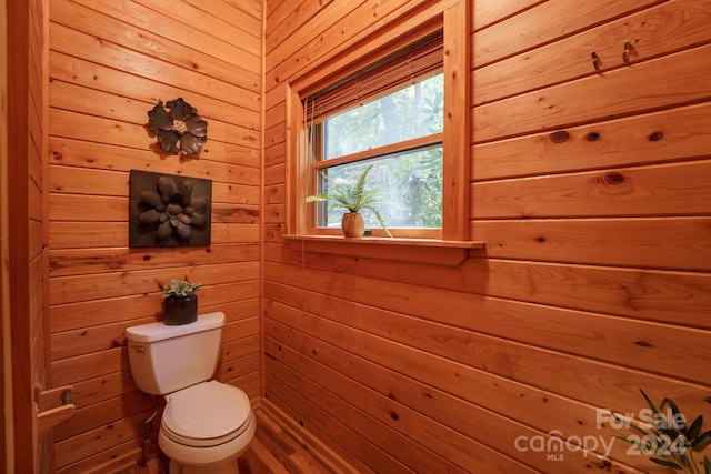 bathroom featuring wood walls and toilet