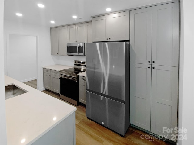 kitchen featuring gray cabinets, sink, light hardwood / wood-style flooring, and stainless steel appliances