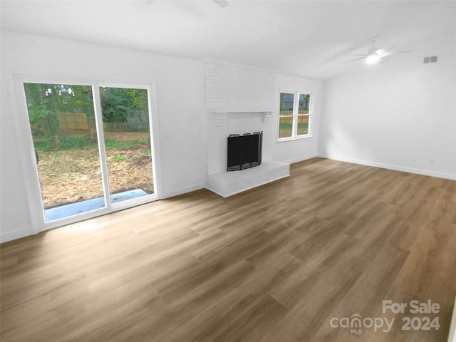 unfurnished living room with ceiling fan, a fireplace, and wood-type flooring