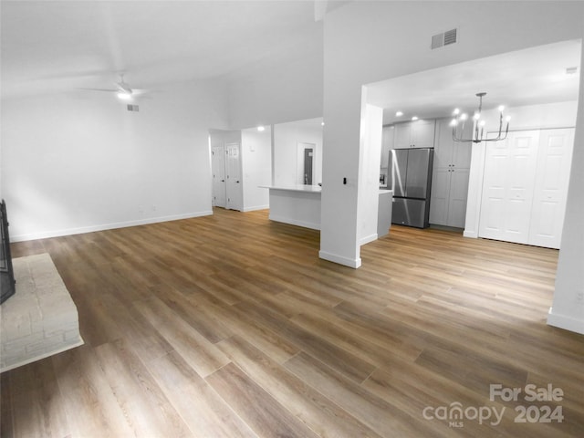 unfurnished living room with ceiling fan with notable chandelier and hardwood / wood-style floors