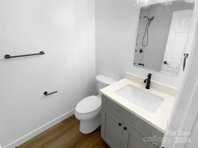 bathroom featuring hardwood / wood-style floors, a tile shower, vanity, and toilet