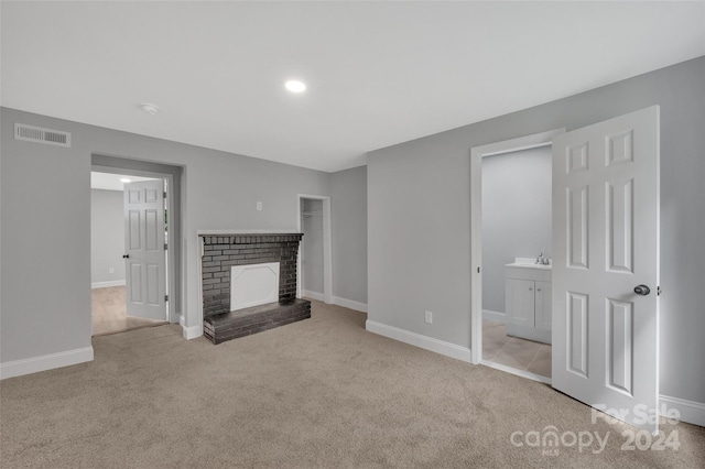 unfurnished living room featuring a brick fireplace and light colored carpet