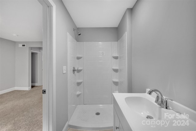 bathroom with tiled shower and vanity