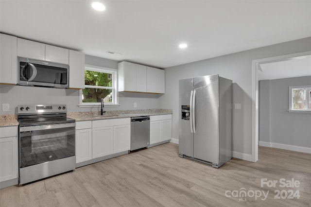 kitchen featuring sink, stainless steel appliances, light hardwood / wood-style floors, and white cabinetry